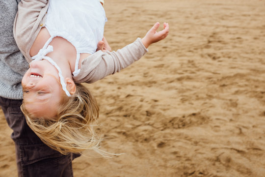 Young girl being swung upside down by father