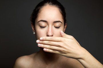 Beautiful young woman covering her mouth with hand. Isolated.