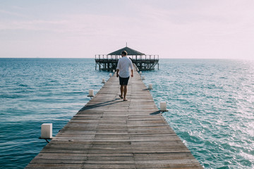Man walking along wooden pier, rear view