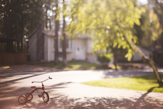 Red Tricycle Sitting Alone in Driveway
