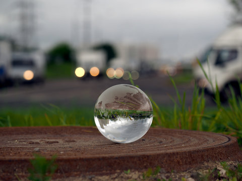 Transparent ball on the hatch near the roadway. Evening lights of cars. In the bowl of a reflection of the electrical towers. Concepts, ideas - Urban ecology, traffic safety. 