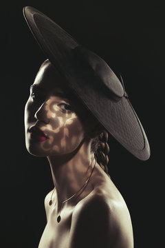 Portrait of woman wearing a black hat in shadow