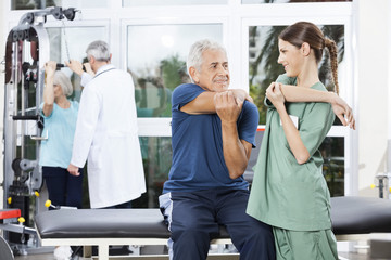 Nurse Guiding Senior Man In Stretching Exercise At Rehab Center