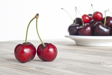 cherries on aged wood on the plate, aged wood and white background