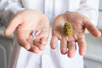 Doctor hand holding bud of medical cannabis and pills - obrazy, fototapety, plakaty