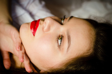 green eyes sensual pinup girl romantic beautiful young woman with big lips having fun touching herself posing relaxing lying on a white bed & looking up at copy space closeup image