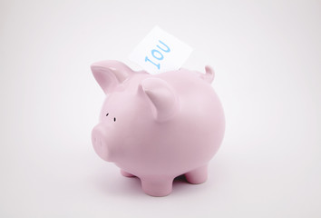 Pink piggy bank with IOU sticking out of its coin slot.