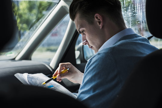 Young man reading document in car