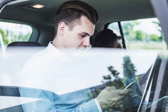 Young man with cell phone and woman in car