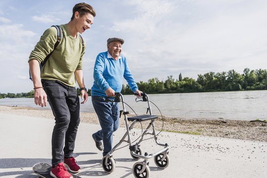 Grandfather and grandson strolling together at riverside
