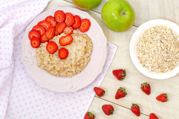 Oatmeal with strawberries and apples on the table. The view from