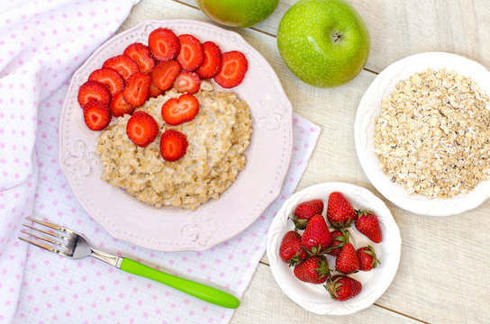 Oatmeal with strawberries and apples on the table. The view from