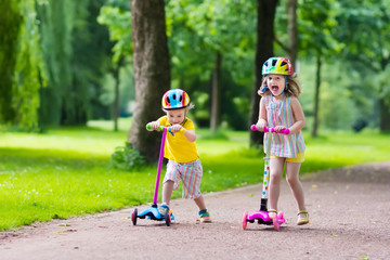 Little kids riding colorful scooters