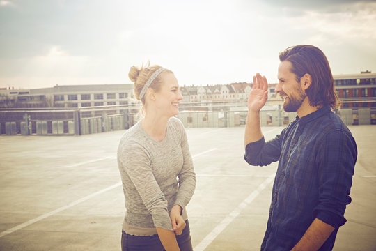 Mid adult couple giving high five on rooftop parking lot - Powered by Adobe