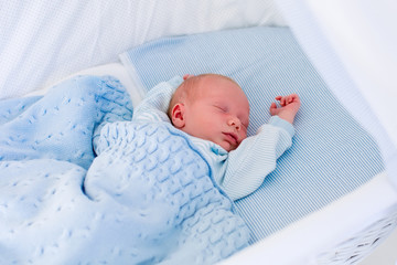 Newborn baby boy in white bassinet
