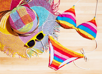 Summer colorful bikini, straw hat and sunglasses on the wood table. Vacation fashion and shopping image.