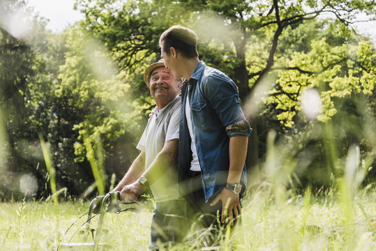 Happy grandfather walking with his grandson in nature