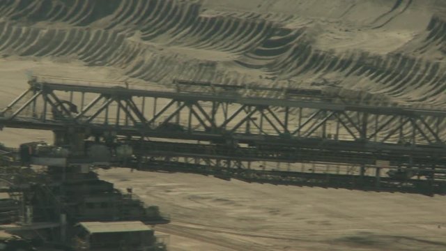 Open-cast mining. Pan on conveyor from giant bucket-wheel excavator. Medium shot. Surface mine.