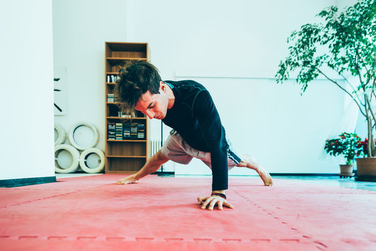 Man in gym, hand behind back doing push up