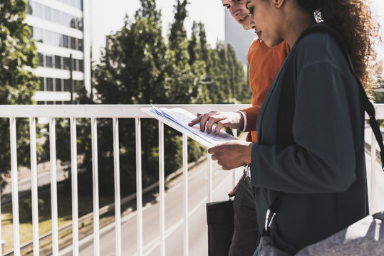 Young man and woman sharing document outdoors