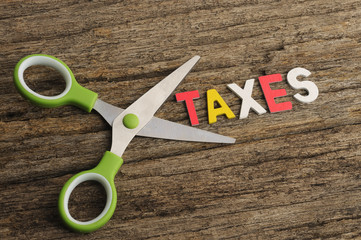 Scissors With TAXES Word on Wooden Background