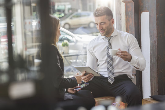 Businessman and businesswoman with digital tablet and smartphone in a cafe