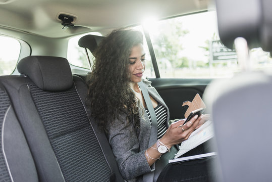 Young woman in car looking at cell phone