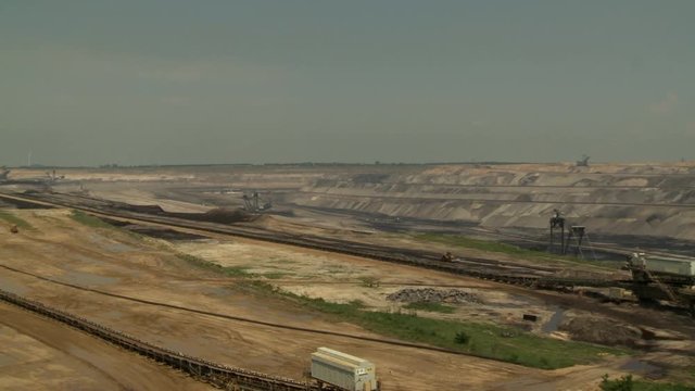 Open-cast mining. Pan over mine with flat conveyors. Establishing shot. Surface mine.