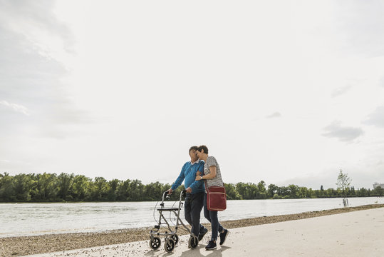 Senior man strolling with daughter at riverside