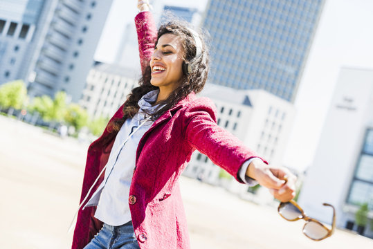 Happy young woman with headphones moving outdoors