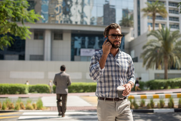 Young man on pedestrian crossing talking on smartphone, Dubai, United Arab Emirates