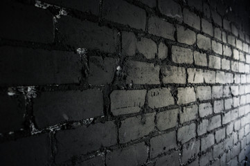 Side view on black brick wall lit by light from the window