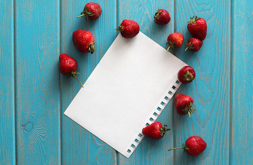 Naklejka na ściany i meble Strawberries on wooden grey desk with white paper sheet.