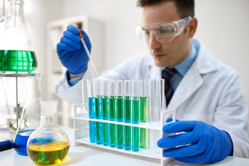 Male scientist using chemistry liquid for research.