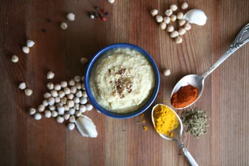 Tuinposter Hummus, chickpea dip, with rosemary, smoked paprika and olive oil in an authentic bowl with pita on a wooden background. © Happy Moments 