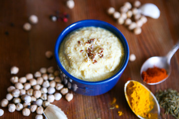 Hummus, chickpea dip, with rosemary, smoked paprika and olive oil in an authentic bowl with pita on a wooden background.