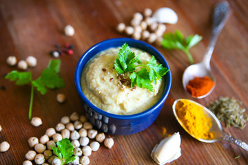 Hummus, chickpea dip, with rosemary, smoked paprika and olive oil in an authentic bowl with pita on a wooden background.
