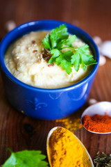 Hummus, chickpea dip, with rosemary, smoked paprika and olive oil in an authentic bowl with pita on a wooden background.