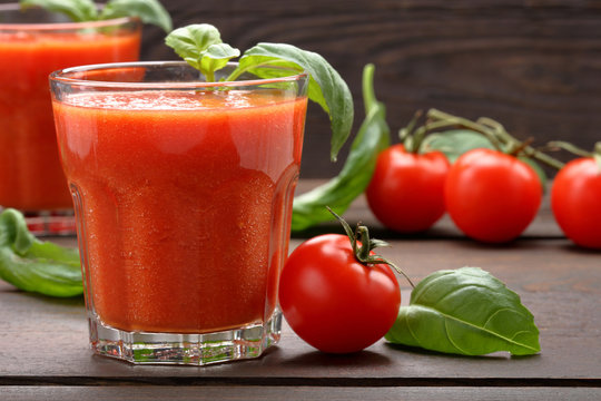 Tomato juice with vegetables on wooden background