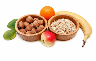 There are Banana,Apple,Orange with Walnuts in the Wooden Plate and Rolled Oats,with Green Leaves,Healthy Fresh Organic Food on the White Background