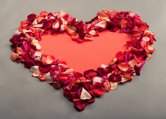 red heart made of rose petals on a grey background
