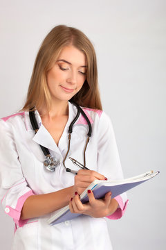 beautiful woman doctor with a stethoscope takes notes