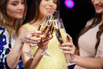 Clinking glasses of champagne in hands on bright lights backgrou