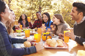 Group of happy friends eat and laugh at a table at a barbecue