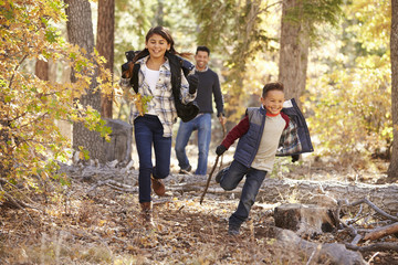 Children in a forest running to camera, father looking on