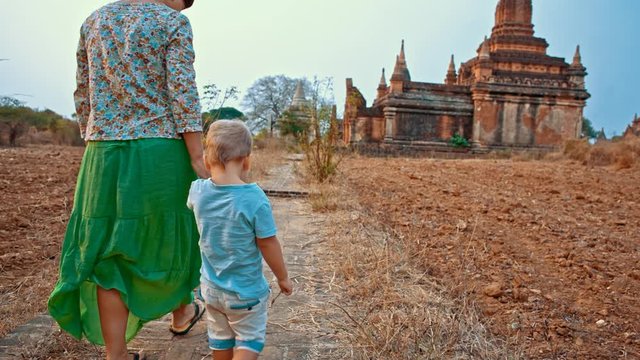 young woman walks with toddler son on the road to temple in the ancient Bagan city in Myanmar (formerly Burma)