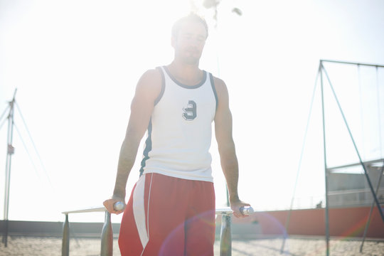 Mid adult man exercising on beach, using gymnastics parallel bars