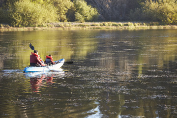 Father and son kayaking on a lake, back view, distant