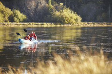 Father and son kayaking together on a lake, front view © Monkey Business