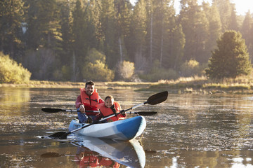 Father and son kayaking on rural lake, front view © Monkey Business